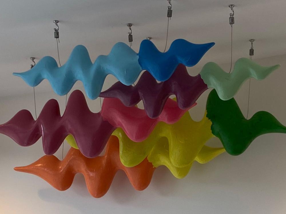 A photo of a collection of the colourful artwork hanging from the ceiling