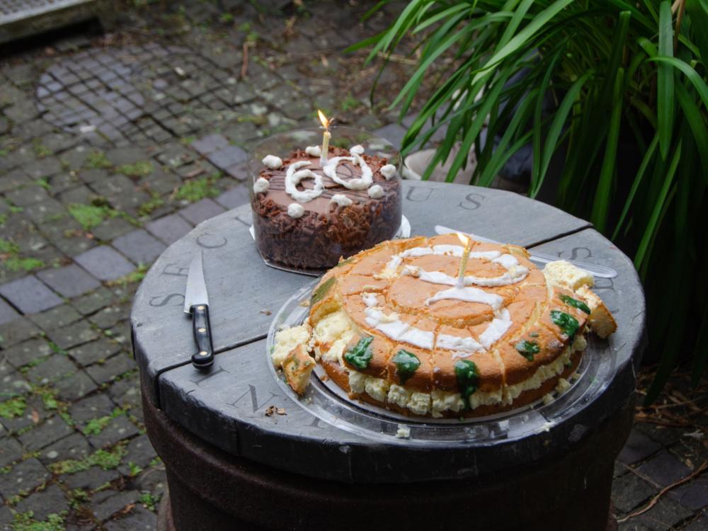 Two cakes on a stone table, one chocolate and one victoria sponge.