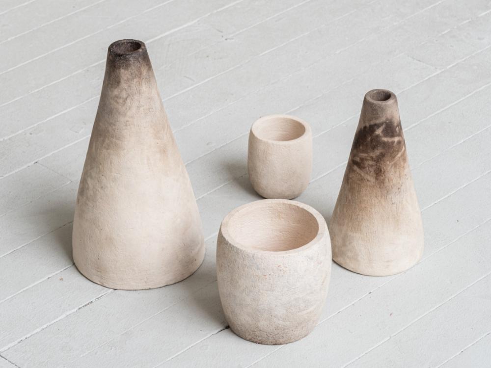 A group of four off-white pots. Two are small, circular pots, two are conical, smaller at the top than the bottom, with dark burn marks towards the top