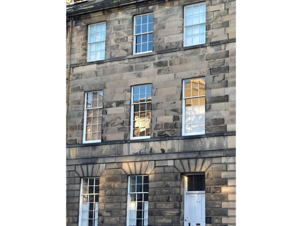 The front of a Georgian townhouse with sash and case windows. The reflection in the glass of the first floor windows is clearly wobbly, indicating the wobbly texture of the glass itself.
