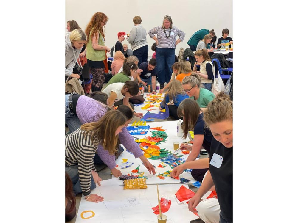 Lots of illustrators working together around a long table, creating colourful work