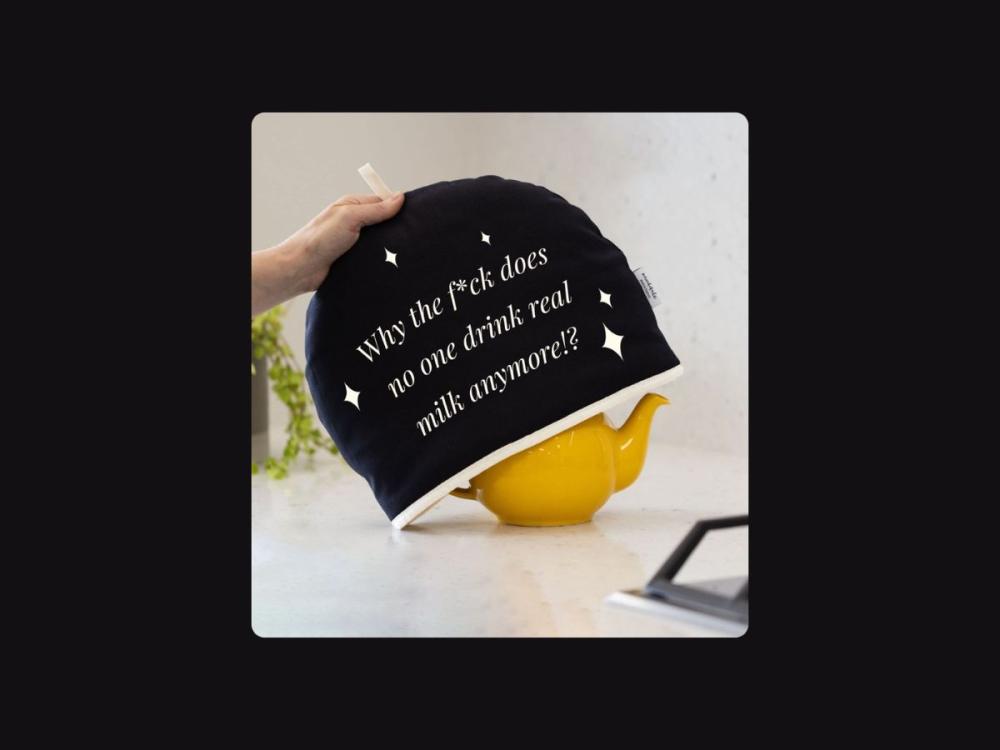 A photograph of someone's hand, lifting a black tea cosy from a yellow teapot. White text on the tea cosy reads: Why the f*ck does noone drink real milk anymore!? 