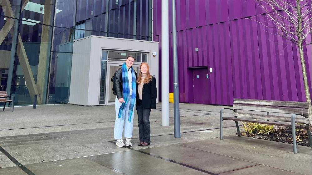 Two students stand outside a purple building