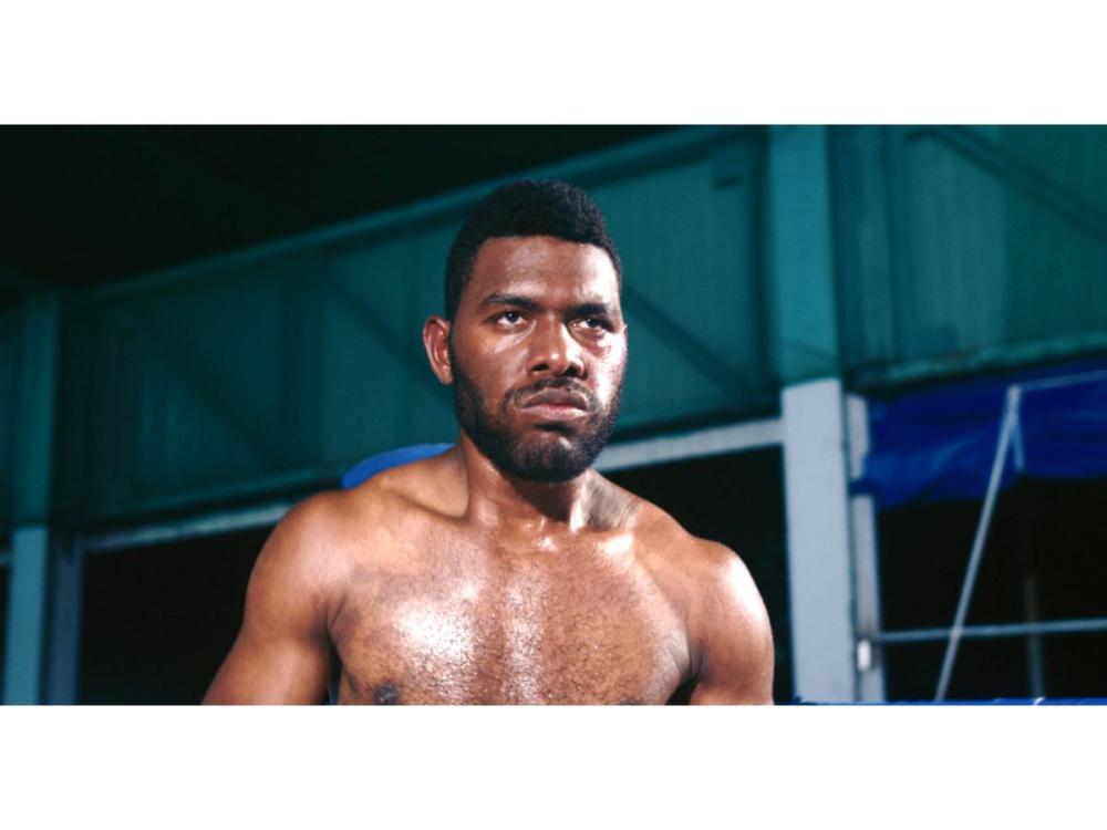 A bare chested man, staring intently ahead. 