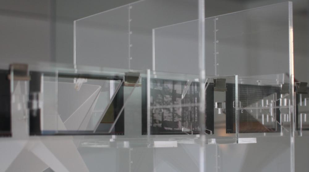 An installation of drawings and photographic prints, hanging on cut acrylic frames.