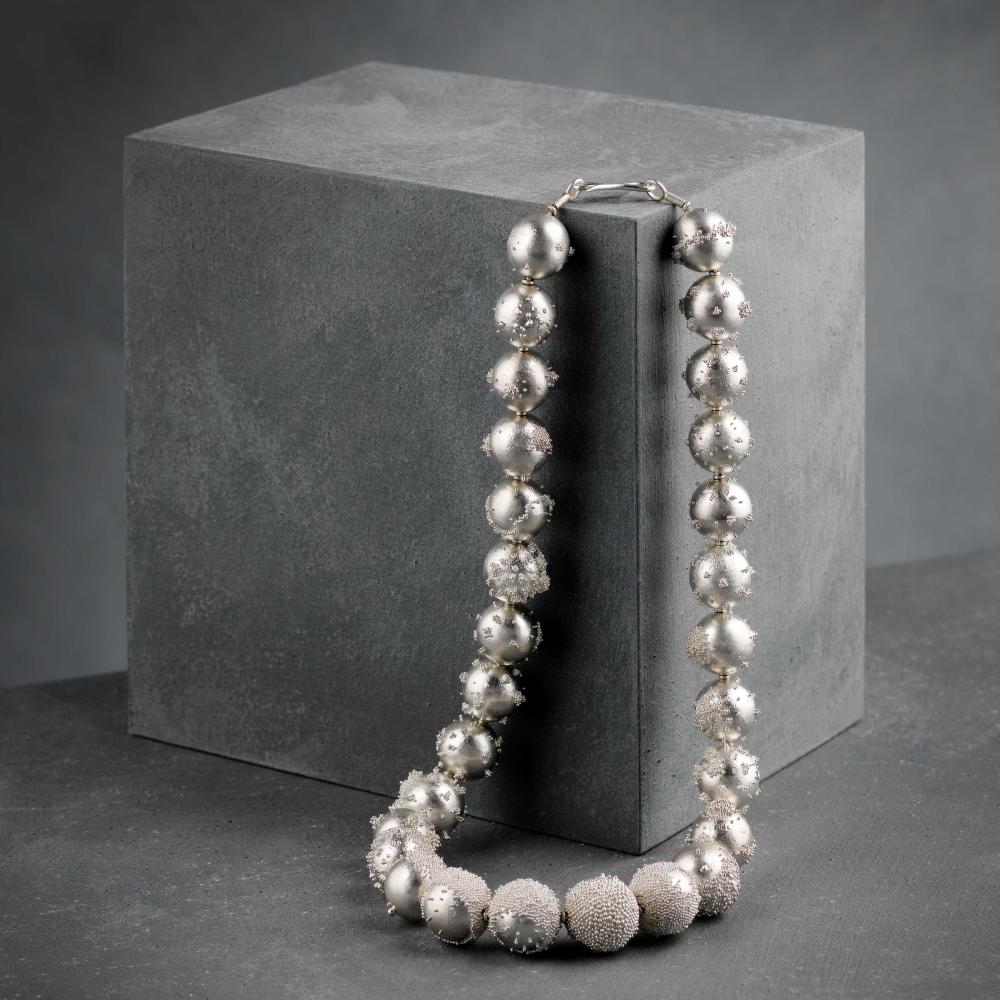 Granulates necklace set against a dark grey background 