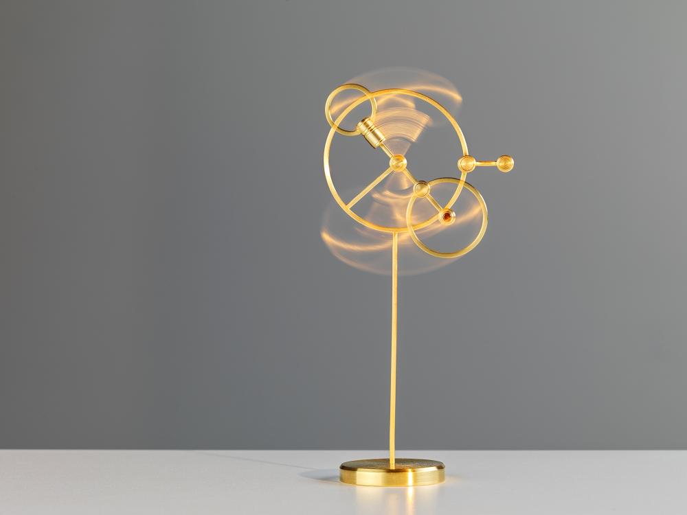 Kinetic sculptural object is captured in motion. A gold plated brass sculpture formed of circular elements that are held on with magnets, some units are sculptural, some wearable. 