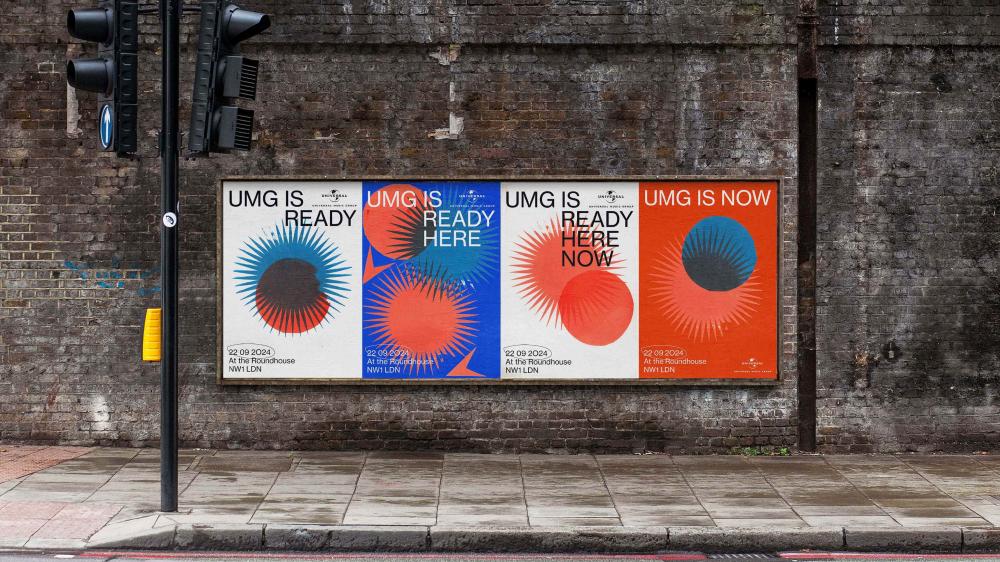 a row of 4 posters on a brick wall by traffic lights, all in the same style but varying colours, including blue, orange and white, advertising an event in London. They have a bold graphic style.