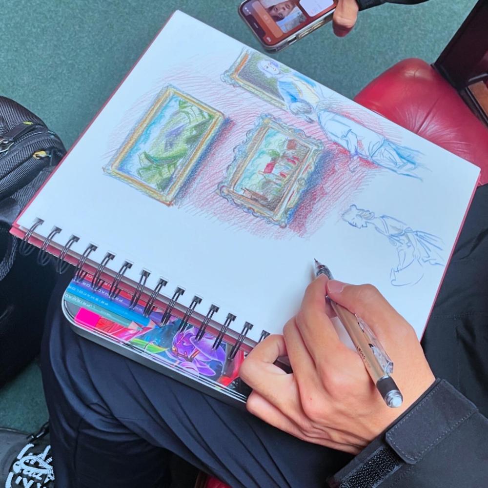 A close up of someone sketching in a notebook, with the drawings showing paintings from an art gallery.