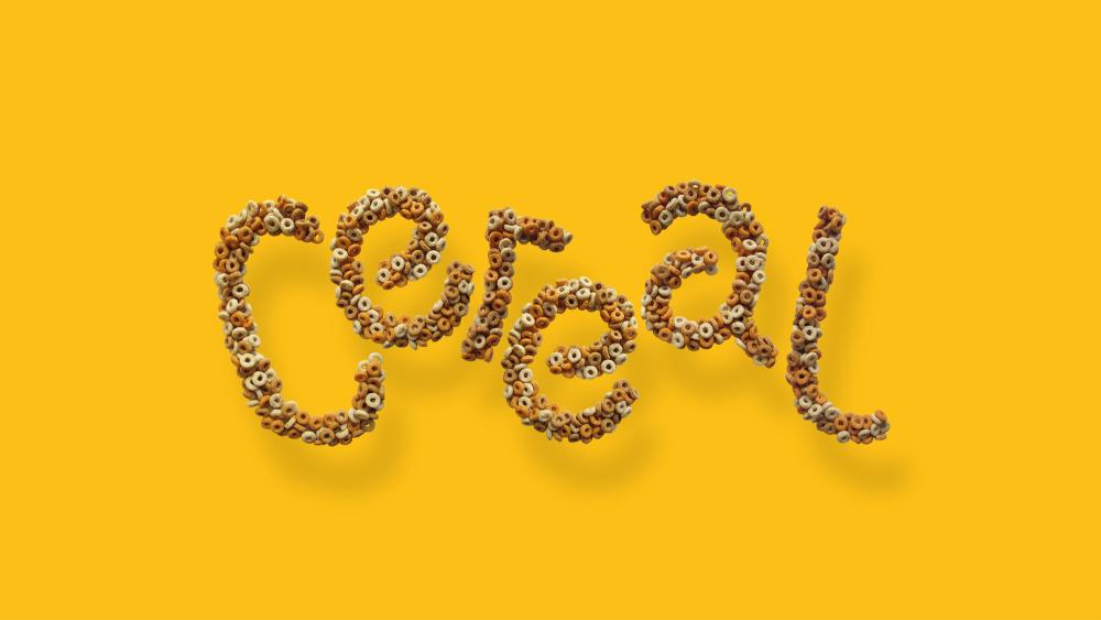 A graphic design concept for the word Cereal, which is written in a hooped cereal in front of a mustard yellow background.