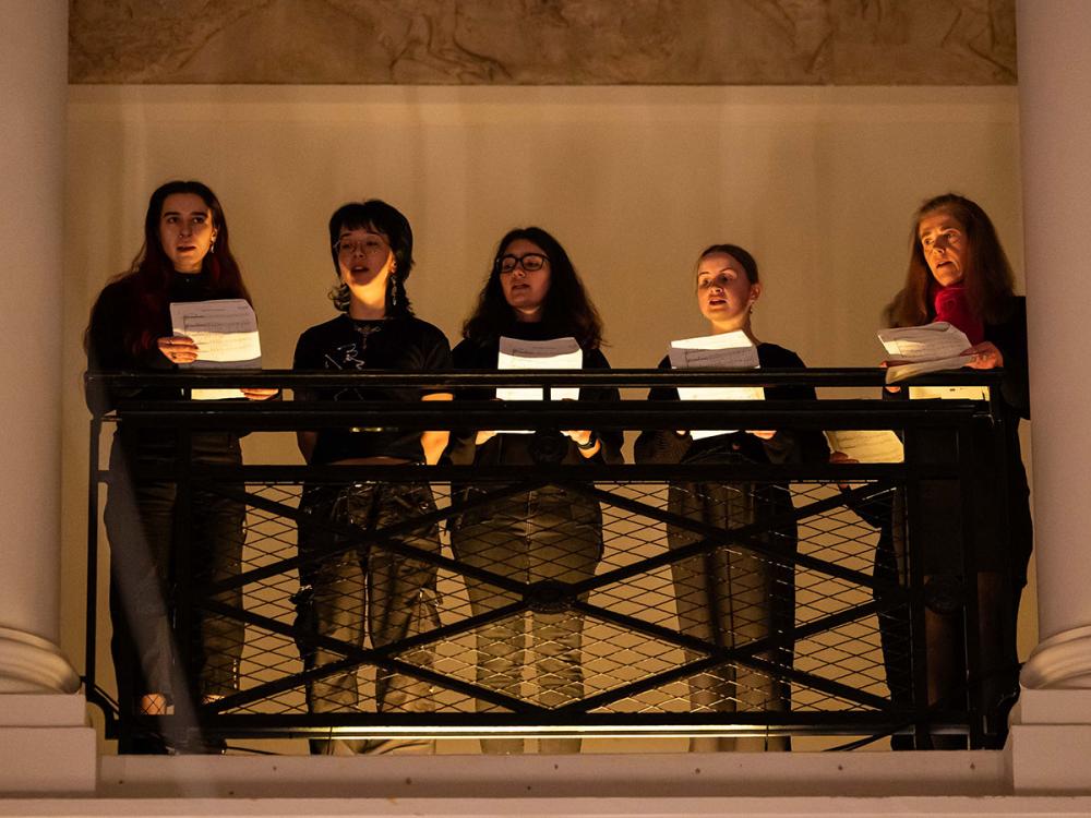 Five members of the choir sing, standing on the Sculpture Court balcony.