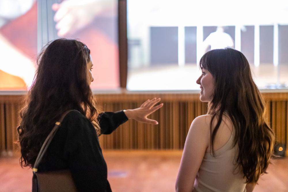 Two people talking in the Authenticity Unmasked: Unveiling AI-Driven Realities Through Art exhibition space.