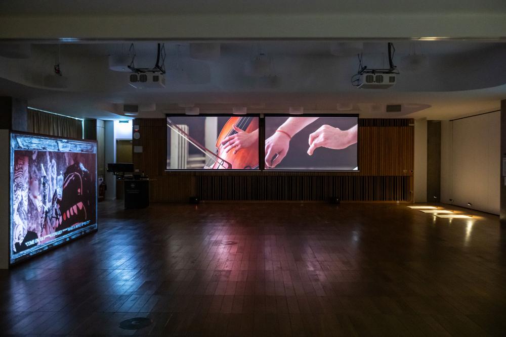 Two screens with pictures of hands on the at The Authenticity Unmasked: Unveiling AI-Driven Realities Through Art exhibition space.
