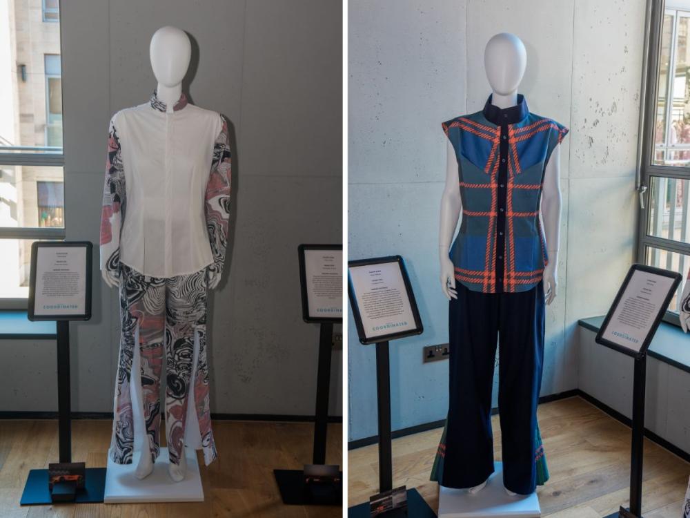 Two sets of garments on mannequins, each with trousers and a top. One has patterns in white, pink and black; the other has dark trousers and a large check pattern on top.