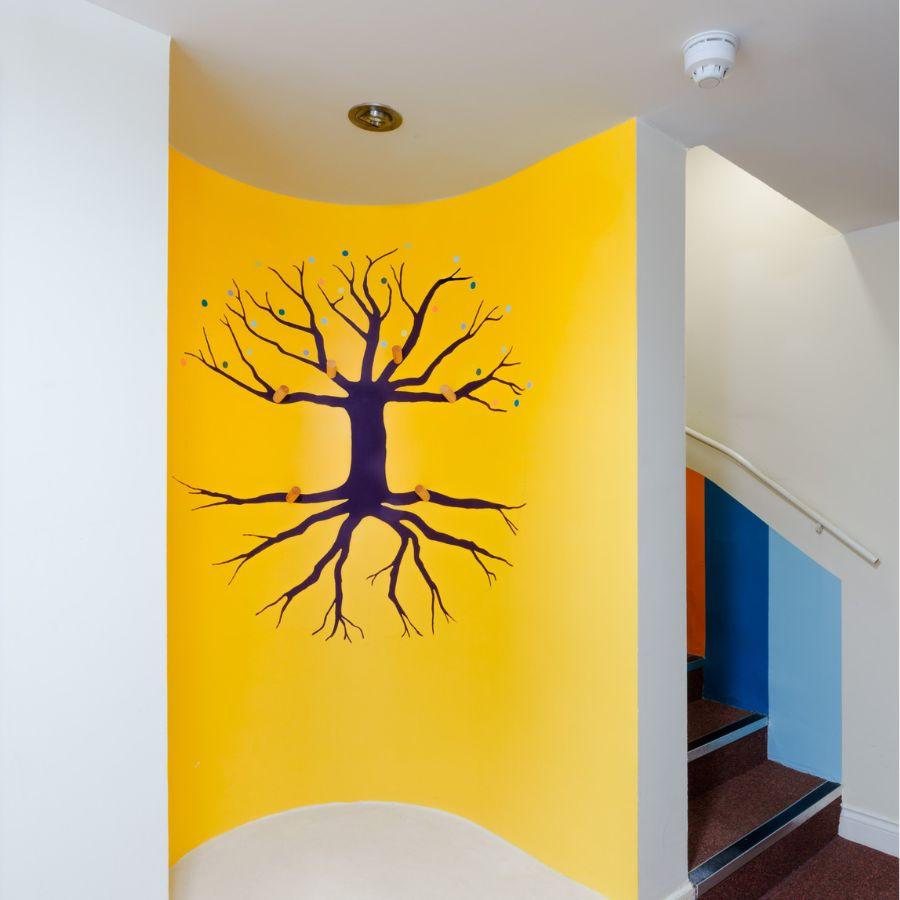 A tree without its leaves has been painted into a curved alcove at the bottom of a staircase.