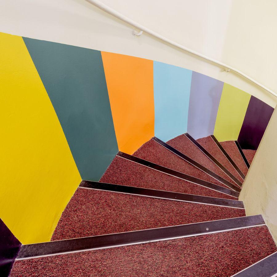 Vertical stripes in bright colours have been painted on to a staircase wall.