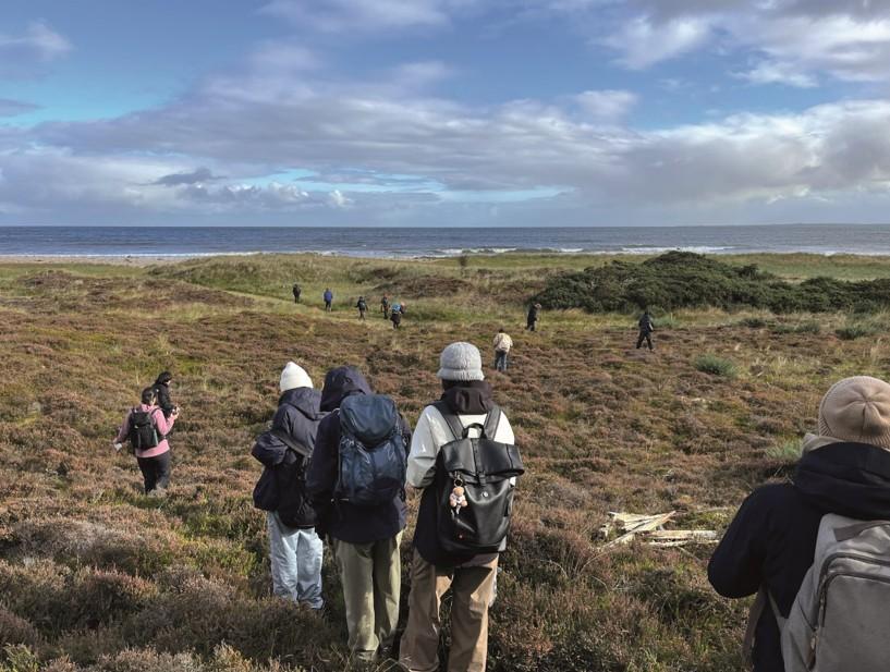 photograph of a group of students walking in the countryside by the sea