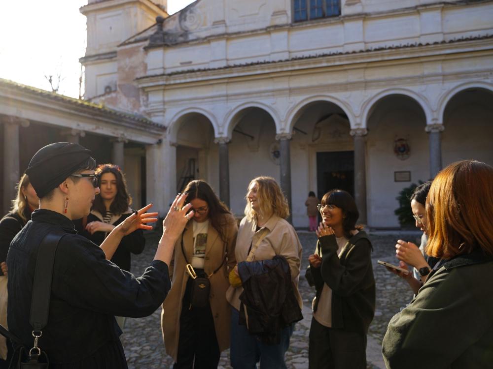 A person stands in a group of students teaching in an early modern church interior