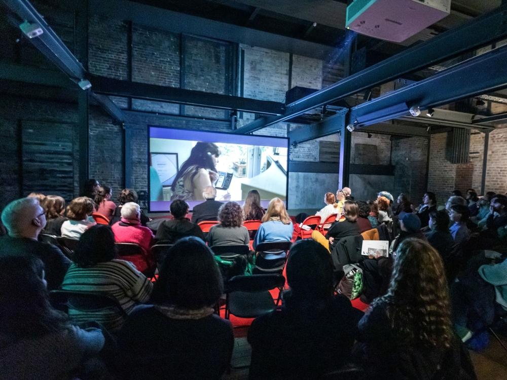 People gather to watch a video installation in a gallery