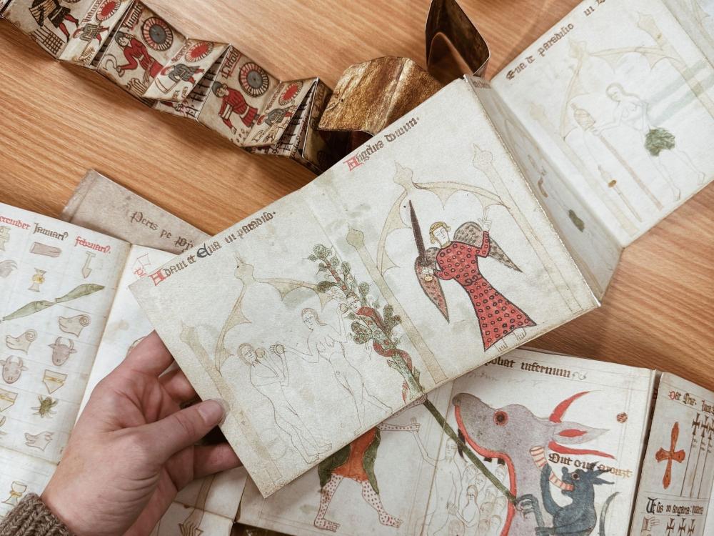A teacher's hand holds replica's of medieval folding calendars for a history of art seminar