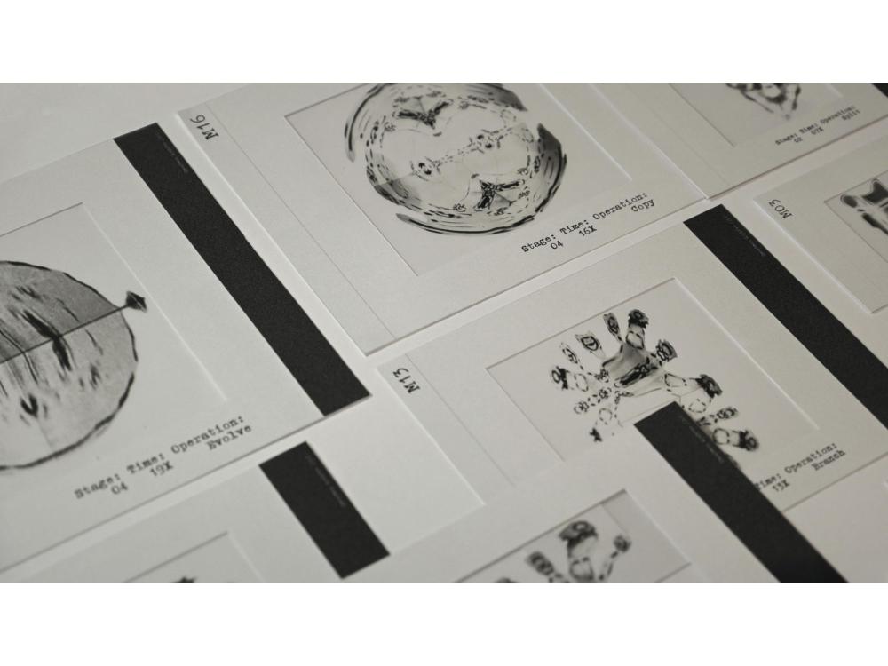 An angled overhead shot of printed cards laid out in a grid, each in a wide white border with a typewriter caption reading "Stage, Time, Operation" followed by terms such as Copy, Evolve, Branch and Split. The images are inky, blurred blobs that appear to mutate from card to card, coded M03, M13 and M16.