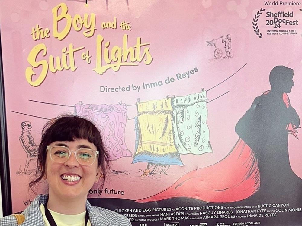 A student stands in front of a poster for their film 'The Boy'.